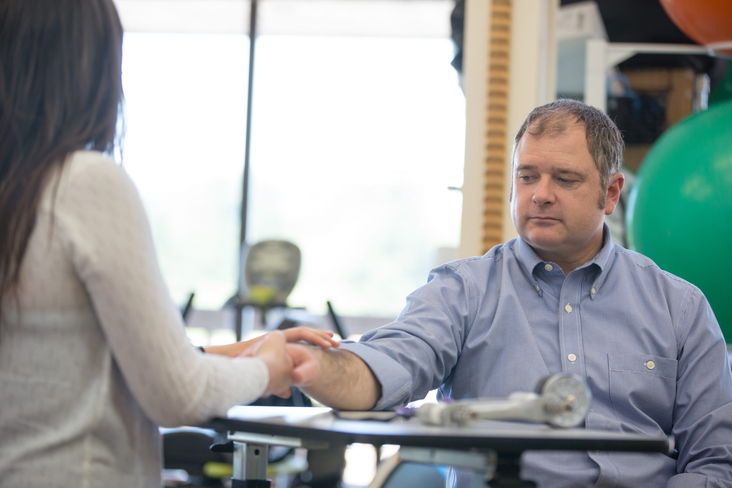 Middle aged man being assessed by a hand therapist in a facility.