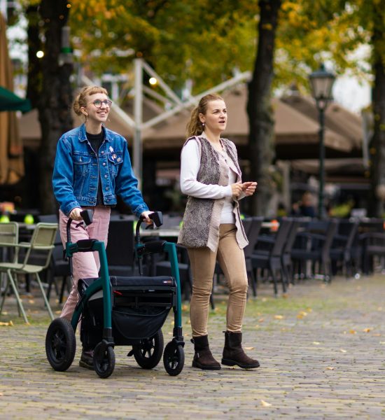 One woman with a walker and her partner enjoying their walk nearby cafes in the Fall